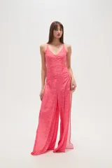 Pantalon de tiro bajo con diseño de aberturas laterales pronunciadas, unidas por argollas metálicas. Presenta un estampado animal print tipo cebra en tonos fucsia y rosado, con corte amplio y fluido.