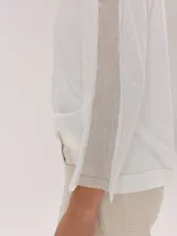 Remera de manga larga color gris claro, con detalle de franjas laterales en contraste color amarillo en las mangas. Presenta un diseño holgado y moderno.