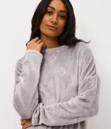 Conjunto de pijama largo de dos piezas confeccionado en tejido fleece suave y abrigado. Incluye una blusa de manga larga con cuello redondo y ajuste en la cintura, y un pantalón con cintura elástica. Ambas prendas presentan una textura grabada con diseño de gatitos.