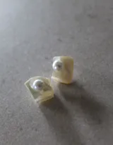 Aros pequeños de nácar con forma cuadrada y perla plateada en el centro.