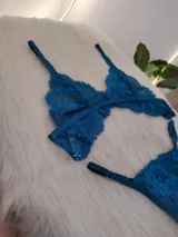 Conjunto de lencería de encaje floral color verde petróleo, compuesto por un corpiño triangular sin aro y una bombacha tipo colaless con tiras laterales ajustables.