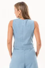 Chaleco de denim fino y liviano color celeste, con silueta entallada, escote en V y cierre frontal con botones de nácar. Presenta un diseño sastrero con terminación en puntas en la delantera.