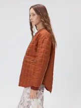 Campera reversible capitoneada con cierre frontal. Un lado es de color negro y el otro es de color beige, ambos con diseño acolchado. Cuenta con cuello redondo, mangas largas y bolsillos laterales.