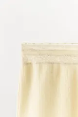 Shorts de tiro medio de tejido pointelle color beige, con cintura elástica y detalle de aplicación de encaje a tono en el ruedo.