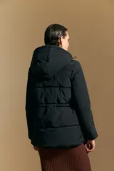 Campera acolchada de nylon en color crema, con capucha ajustable, cierre frontal con botones y cordón de ajuste en la cintura.