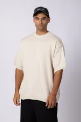 Remera de punto color crema, de manga corta, con cuello redondo acanalado y corte oversize.