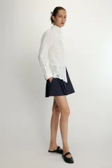 Camisa de manga larga en color blanco, confeccionada con detalles de bordados perforados a tono. Presenta un cuello tipo pañuelo y cierre frontal con botones.