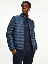Campera acolchada Tommy Hilfiger color azul marino, con cuello alto y cierre de cremallera. Tiene el logo de la marca bordado en el pecho y detalles distintivos en el cuello. Es plegable y repele el agua.