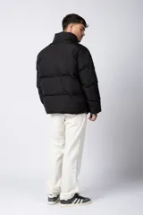 Campera puffer de corte relajado en color verde oscuro, con cuello alto, cierre frontal completo y logo bordado en el pecho.