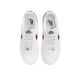 Championes Nike Air Force 1 '07 de corte bajo, color blanco con detalles en azul marino y rojo. Presentan el icónico diseño de la silueta con perforaciones en la puntera, suela de goma con tecnología Air y un gráfico de mano en el talón.