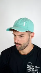 Gorra de gabardina color verde agua con visera curva y bordado pequeño en color blanco en el frente.