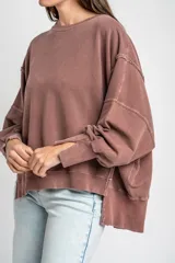 Sweater de algodón peinado con efecto lavado, de corte oversize, cuello redondo y mangas largas con costuras visibles.