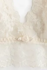 Soutien de encaje con copas acolchadas, breteles finos ajustables y detalle de pequeña rosa en el centro. Presenta un ribete ancho de encaje en la base y cierre de corchetes en la espalda.