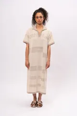 Vestido midi tejido de punto color beige, con cuello polo, mangas cortas y diseño calado con motivos geométricos.