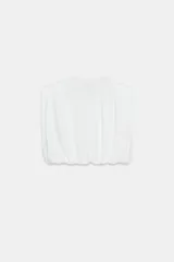 Top de algodón con cuello redondo, diseño sin mangas con hombreras marcadas y detalle de pliegues. Presenta un bajo acabado tipo globo con elástico.
