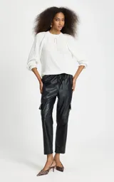 Blusa Aretha de Le Lis Blanc confeccionada en tejido de punto acanalado blanco, con corte recto, escote redondo decorado con un delicado lazo frontal, mangas largas ligeramente abullonadas con puños ajustados y dobladillo acanalado.