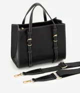 Cartera satchel mediana de color marrón, confeccionada en poliuretano con diseño estructurado, costuras en contraste y herrajes metálicos dorados. Cuenta con doble asa de mano, correas decorativas verticales con hebillas en la parte frontal y una correa larga ajustable y desmontable para llevar al hombro o cruzada.