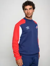 Buzo de felpa con diseño de bloques de color, predominantemente rojo en el cuerpo y azul marino en las mangas y hombros. Presenta el escudo del Club Nacional de Football y el logo de Umbro en el pecho.