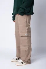 Pantalón tipo carpintero de corte relaxed fit y tiro medio, confeccionado en denim negro con costuras a contracolor en blanco. Presenta múltiples bolsillos cargo laterales, un bolsillo con cierre en la parte inferior y presillas utilitarias.