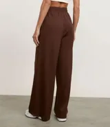 Pantalón de mujer color marrón oscuro, de corte recto y tiro alto, confeccionado en modal con poliéster y elastano. Presenta cintura elástica y un detalle de franja contrastante en las mangas de la chaqueta a juego.
