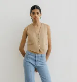 Chaleco color beige a la cintura, confeccionado en lino con botones.