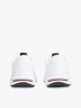 Zapatillas deportivas Tommy Hilfiger de corte bajo, color blanco, confeccionadas en tejido de punto de poliéster, con forro de poliéster, plantilla extraíble de poliuretano y suela de EVA. Presentan logo Hilfiger en relieve en el lateral y cinta distintiva en la entresuela.