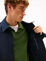 Campera azul marino de tejido técnico de Tommy Hilfiger, con cierre frontal de cremallera, cuello camisero, bolsillos laterales y parche engomado en la manga.