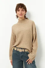 Polera gris de tejido tramado, cuello alto y mangas holgadas.