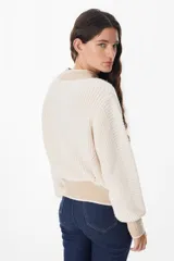 Sweater de punto grueso con diseño bicolor, cuerpo en color crema y detalles en color beige en cuello, puños y ruedo. Presenta mangas largas con caída relajada y cuello redondo.