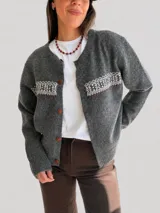 Cárdigan de punto azul marino con diseño jacquard en la parte superior del pecho. Presenta cuello redondo, cierre frontal con botones marrones y puños y ruedo acanalados.