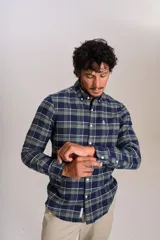 Camisa de manga larga confeccionada en tejido de franela con estampado de cuadros en tonos azul marino y verde. Presenta cuello abotonado, cierre frontal con botones y un bolsillo en el pecho con el logo bordado de la marca.