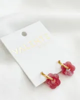 Aros colgantes con aro dorado de acero y dije de flor de acrílico color rosado. El diámetro del aro es de 1,5cm y el diámetro de la flor es de 1,5cm.