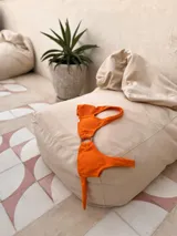 Top de bikini azul marino con brillo dorado, escote pronunciado y argolla de madera en el centro. Tiene tirantes anchos y se ata en la espalda.