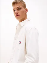Camisa blanca de algodón con textura moteada, corte oversize, cuello inglés, bolsillo de parche en el pecho y parche de Tommy Jeans en el bolsillo.