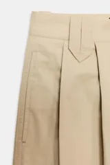 Pantalón de tiro alto en color beige, con pinzas delanteras, bolsillos laterales y bajo con vuelta. Presenta un cierre frontal con cremallera, botón interior y gancho.