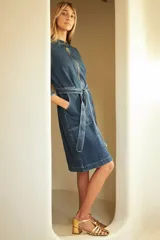 Trench de jean elastizado azul con cierre delantero, frunce en la cintura y lazo para atar.
