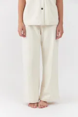 Conjunto de dos piezas color blanco off-white, compuesto por una camisa de manga corta con cuello camisero y bolsillos frontales, y un pantalón largo de corte recto y holgado.