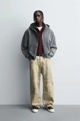 Pantalón de corte baggy fit confeccionado en tejido de algodón con textura y efecto lavado. Presenta diseño de cinco bolsillos, cierre frontal con cremallera y botón.