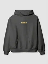 Hoodie gris oscuro con capucha, corte boxy y bolsillo tipo canguro. Presenta un pequeño estampado frontal con tres cuadros amarillos que contienen cruces negras.