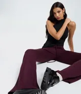 Pantalón de sastrería para mujer en color bordó, con diseño flare acampanado. Cuenta con un lazo ajustable en la cintura y detalle de raya marcada en las piernas. Confeccionado en tejido de viscosa con elastano.