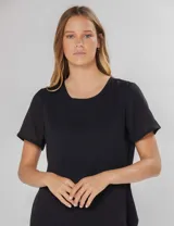 Blusa negra de manga corta con pequeños frunces en los hombros, escote redondo y abertura en la espalda con botón y pin metálico con logo.