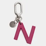 Llavero o charm para accesorios con forma de letra H en color fucsia, con gancho metálico y dije circular pequeño con la marca Bubba grabada.