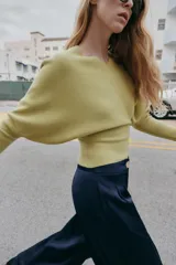 Jersey de punto color verde lima, con cuello pico y manga larga de sisa ancha que se estrecha hacia la muñeca.