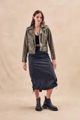 Campera corta color verde oliva de cuero sintético con cuello clásico, cierre frontal asimétrico con cremallera, bolsillos con cremallera y solapa, y detalles de costuras en los hombros.