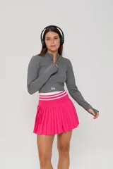 Pollera short deportiva fucsia con diseño plisado en los laterales y cintura elástica ancha con rayas blancas. Incluye bolsillos laterales.