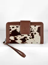 Billetera grande de cuero con estampado de vaca en blanco y marrón. Tiene cierre con broche a presión y correa de mano.