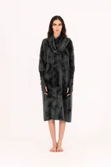 Vestido de tejido de punto gris oscuro con efecto tie-dye o marmolado, silueta amplia y largo midi. Posee cuello tortuga caído y mangas largas con abertura para el pulgar.