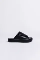 Sandalia negra de cuero vacuno con plataforma gruesa forrada en napa. Presenta una tira ancha con textura gofrada y cierre de velcro ajustable.