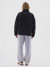 Campera marrón claro con diseño acolchado de rombos, cuello alto, cierre frontal con cremallera, bolsillos laterales y mangas largas con rayas blancas.