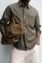 Camisa de corte relajado confeccionada en una mezcla de lyocell y algodón con efecto lavado. Presenta cuello solapa, manga larga con puños abotonados, bolsillo de plastrón en el pecho y cierre frontal con botones.